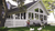 A nice house, dogs in backyard, and white picket fence